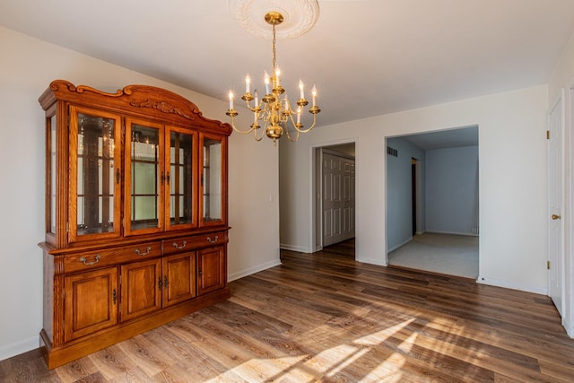 unfurnished dining area with wood-type flooring and an inviting chandelier