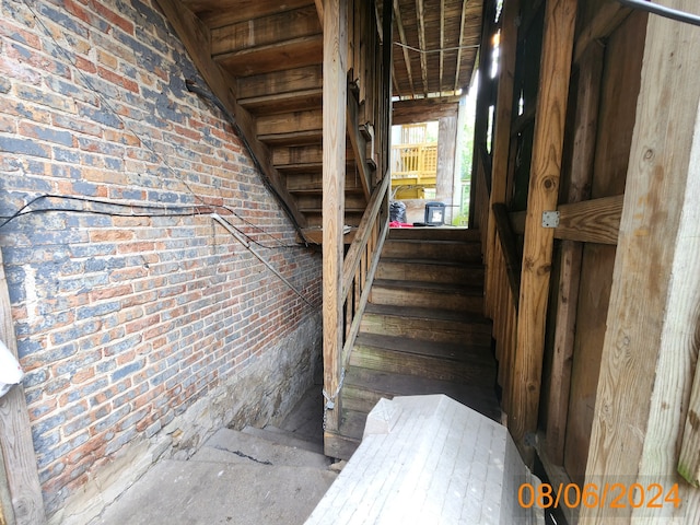 staircase featuring brick wall