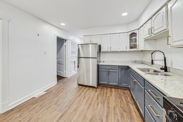 5092 W Monroe St, Chicago, IL 60644 - kitchen with appliances with stainless steel finishes, a sink, gray cabinets, light wood finished floors, and white cabinetry