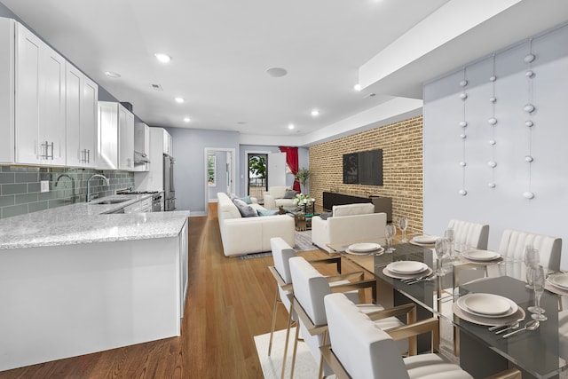 dining room featuring a fireplace, sink, and light hardwood / wood-style flooring