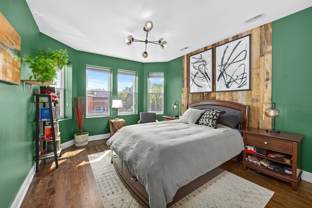 bedroom with dark hardwood / wood-style flooring and an inviting chandelier