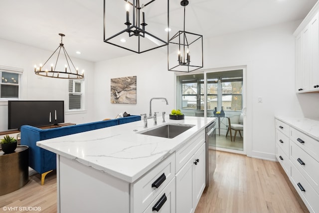 kitchen featuring pendant lighting, a center island with sink, sink, light hardwood / wood-style flooring, and white cabinetry