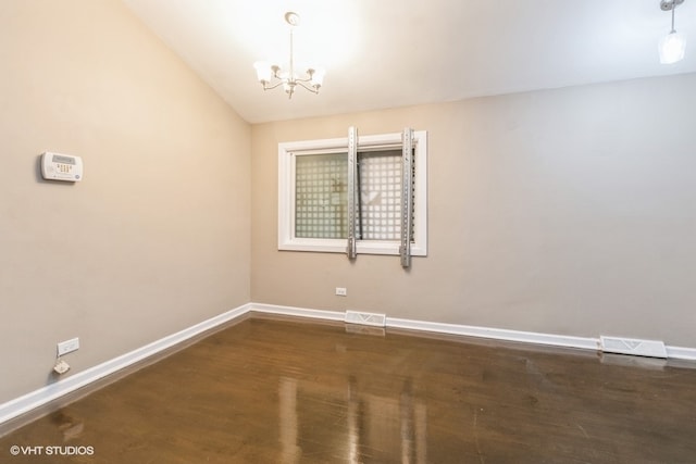 empty room featuring lofted ceiling, a chandelier, and dark hardwood / wood-style floors