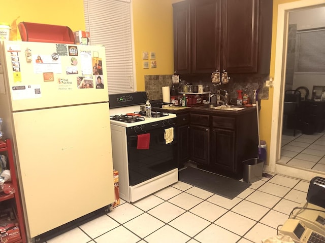 kitchen with sink, white appliances, dark brown cabinetry, and light tile patterned flooring