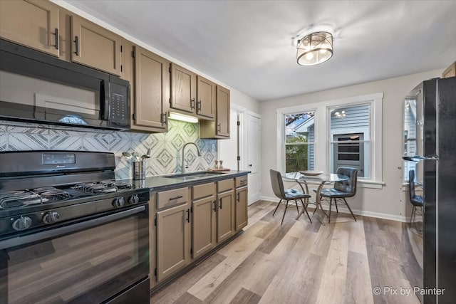 kitchen with black appliances, decorative backsplash, light wood-type flooring, and sink