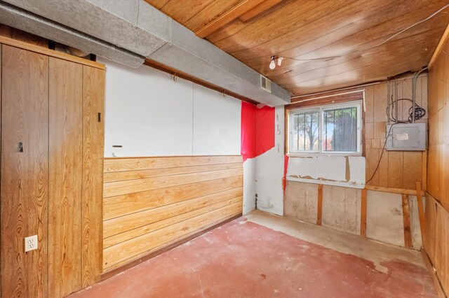 basement with wood walls, wood ceiling, and electric panel