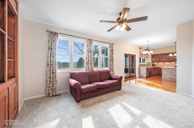 carpeted living room featuring ceiling fan with notable chandelier