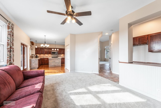 carpeted living room featuring ceiling fan with notable chandelier