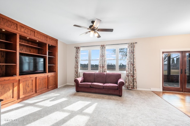 carpeted living room featuring built in features, french doors, and ceiling fan