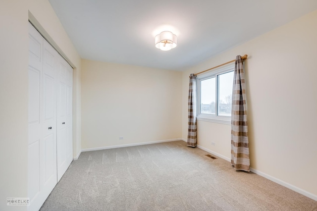 unfurnished bedroom featuring light colored carpet and a closet