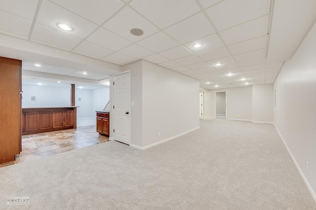 basement with light colored carpet and a paneled ceiling