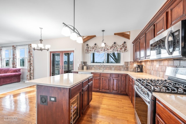 kitchen with sink, hanging light fixtures, backsplash, stainless steel appliances, and a center island