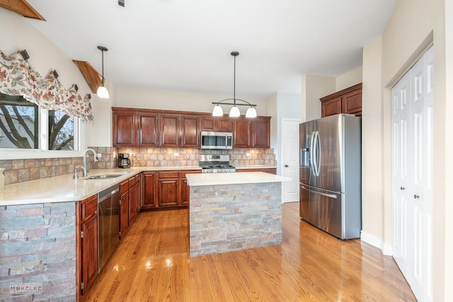 kitchen with stainless steel appliances, decorative light fixtures, a center island, and sink