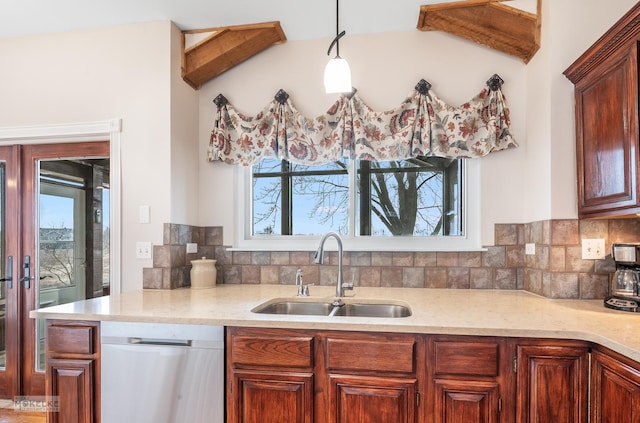 kitchen featuring dishwasher, sink, hanging light fixtures, and backsplash