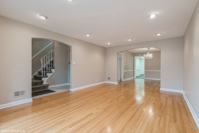 unfurnished room with light wood-type flooring and an inviting chandelier