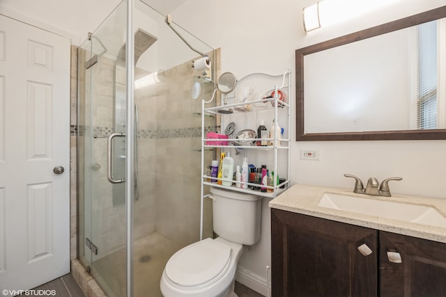 bathroom featuring toilet, an enclosed shower, and vanity