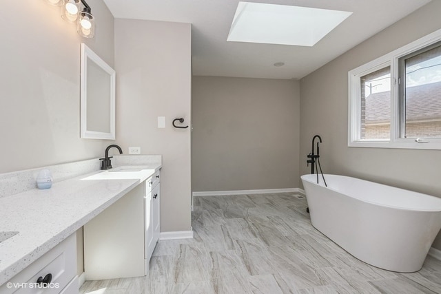 bathroom featuring a skylight, a bathing tub, and vanity