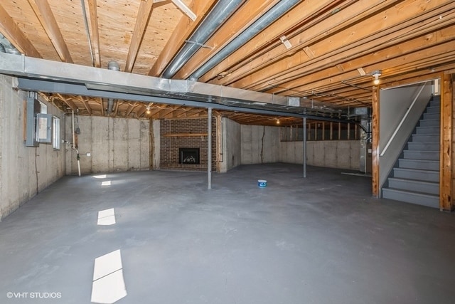 basement with electric panel and a fireplace