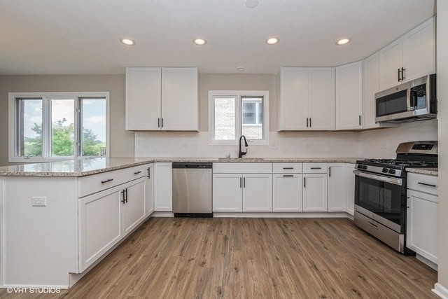 kitchen featuring sink, white cabinets, light hardwood / wood-style floors, and appliances with stainless steel finishes