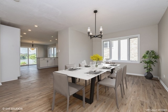 dining room with a chandelier, a healthy amount of sunlight, and light wood-type flooring