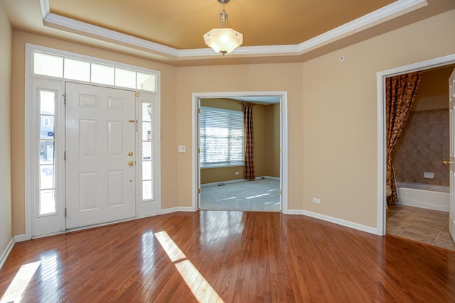 foyer with a tray ceiling, light hardwood / wood-style floors, and ornamental molding