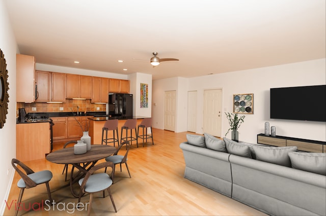 living room featuring light hardwood / wood-style floors, ceiling fan, and sink