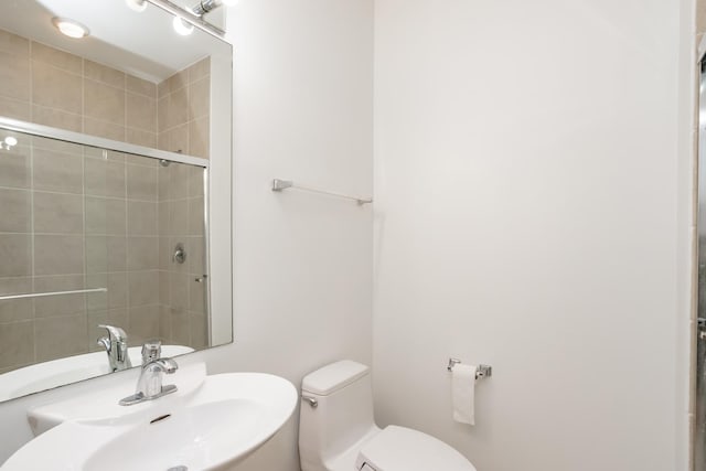 bathroom with sink, an enclosed shower, and toilet