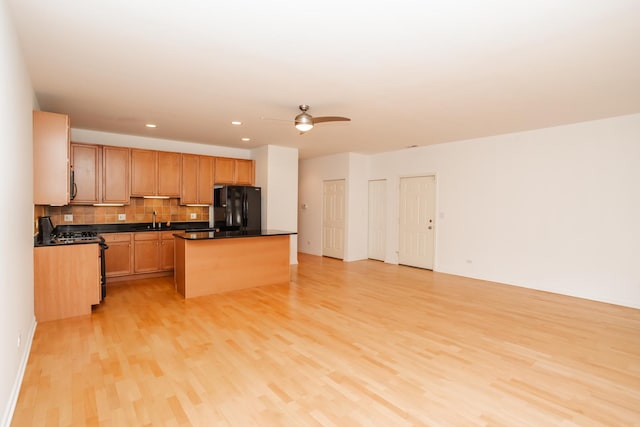 kitchen featuring a center island, sink, light hardwood / wood-style flooring, decorative backsplash, and black appliances