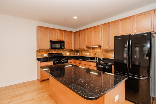 kitchen with a center island, black appliances, sink, light hardwood / wood-style flooring, and tasteful backsplash