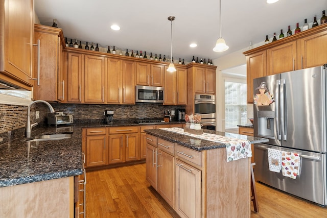 kitchen featuring pendant lighting, sink, light wood-type flooring, a kitchen island, and stainless steel appliances