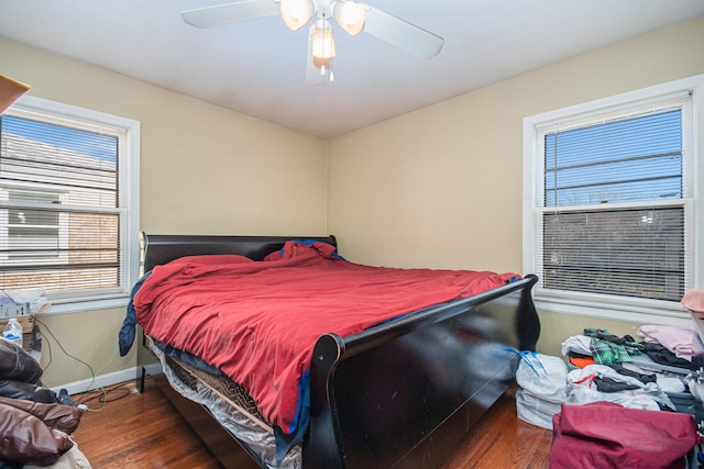 bedroom with ceiling fan, multiple windows, and dark hardwood / wood-style flooring