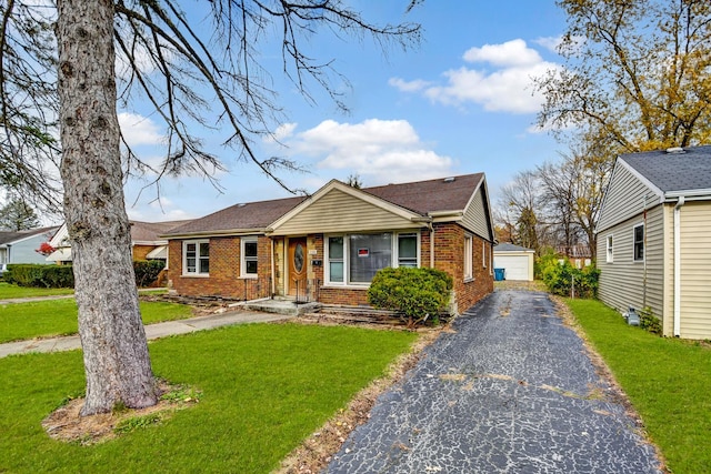 view of front of home with brick siding, a garage, an outbuilding, and a front yard