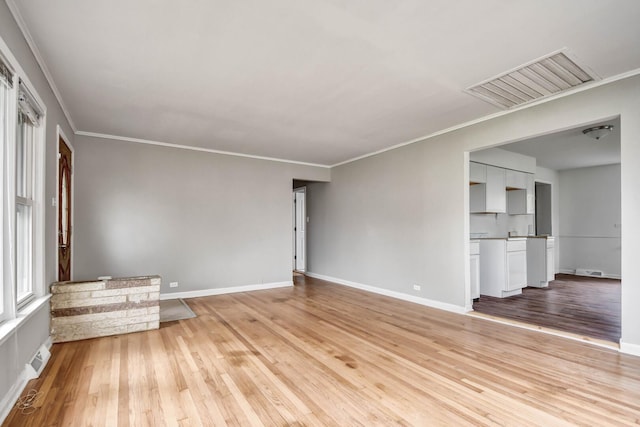 unfurnished living room with light wood-style floors, baseboards, and crown molding