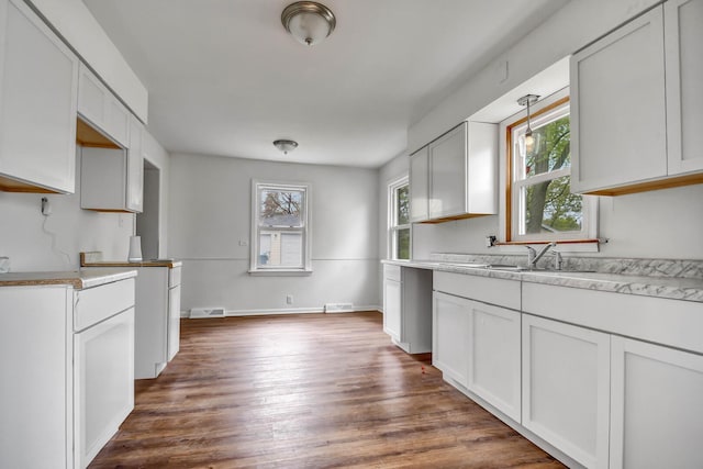 kitchen with light countertops, dark wood finished floors, a wealth of natural light, and a sink