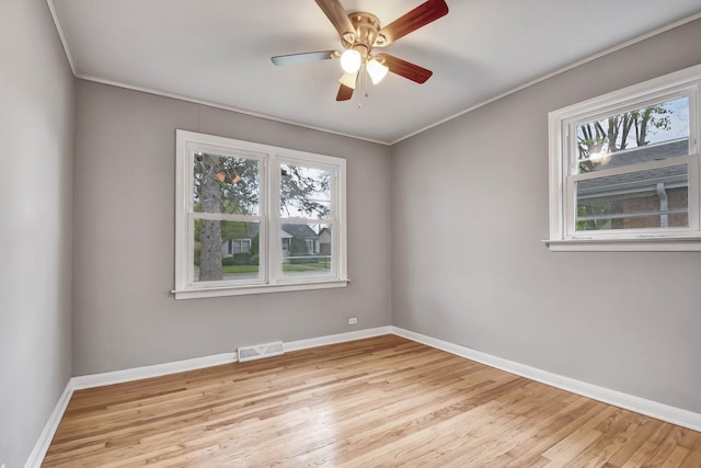 empty room with a healthy amount of sunlight, wood finished floors, and visible vents