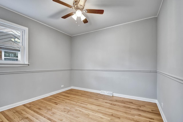unfurnished room with crown molding, baseboards, visible vents, and wood finished floors