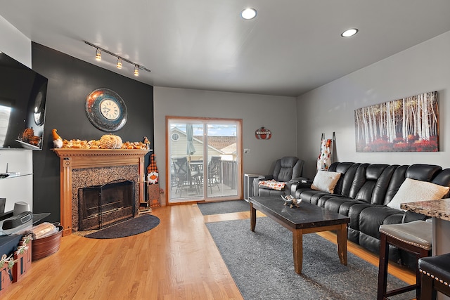 living room with a premium fireplace, rail lighting, and wood-type flooring