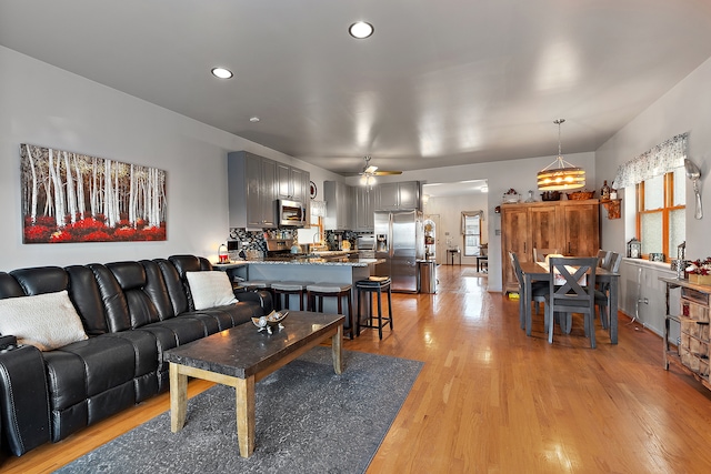 living room with light hardwood / wood-style flooring and ceiling fan with notable chandelier