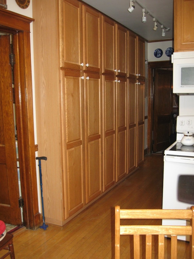 kitchen featuring hardwood / wood-style floors, white appliances, and rail lighting