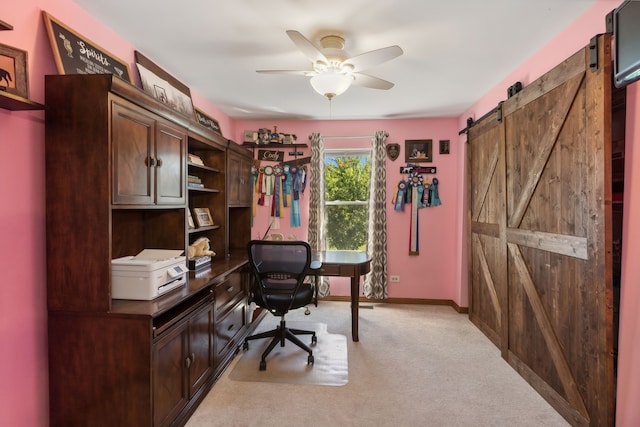 carpeted office with a barn door and ceiling fan