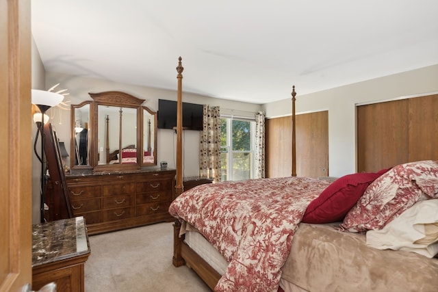 bedroom with light carpet and two closets