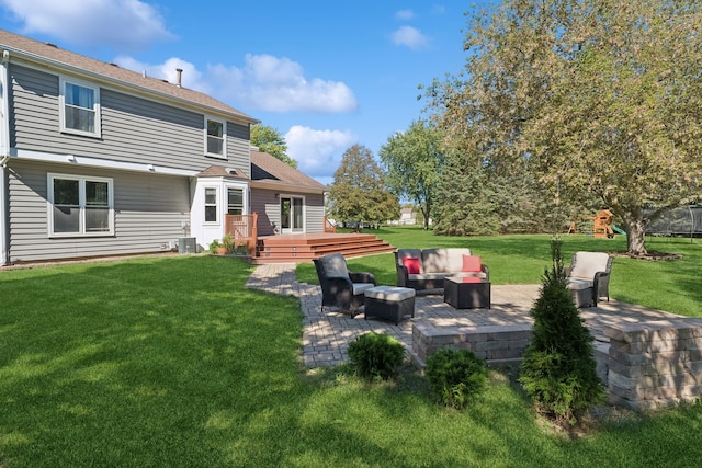 back of property with a wooden deck, an outdoor living space, a yard, and a patio