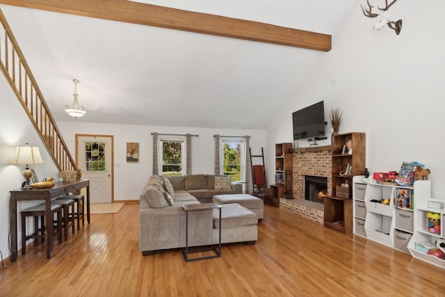 living room featuring beamed ceiling, high vaulted ceiling, light hardwood / wood-style floors, and a brick fireplace