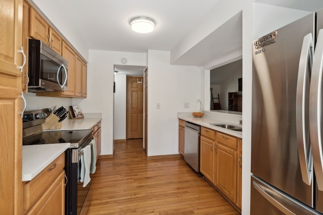 kitchen with appliances with stainless steel finishes, light hardwood / wood-style floors, and sink