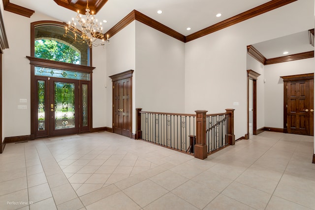 tiled foyer entrance featuring a high ceiling, ornamental molding, and a notable chandelier