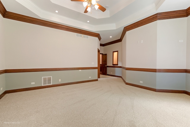 carpeted spare room with ceiling fan, a raised ceiling, and ornamental molding