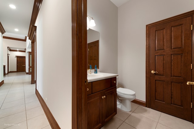 bathroom with tile patterned floors, crown molding, vanity, and toilet