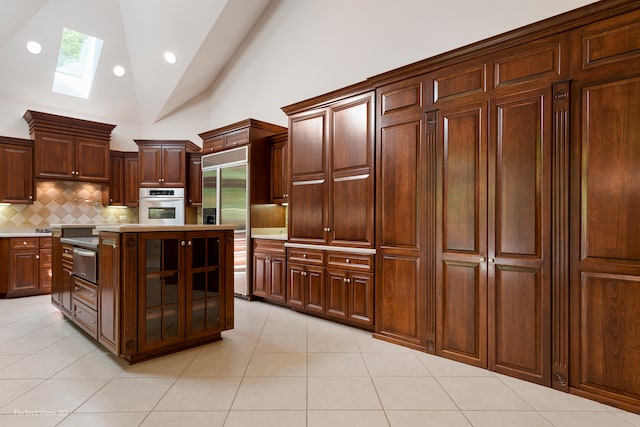 kitchen with a skylight, white oven, stainless steel built in refrigerator, dark brown cabinets, and a kitchen island