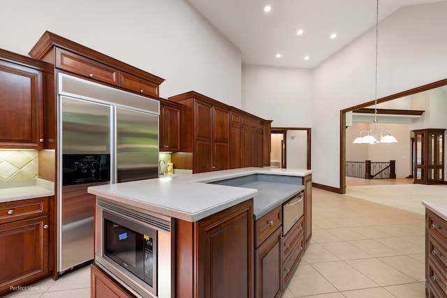 kitchen featuring hanging light fixtures, tasteful backsplash, high vaulted ceiling, built in appliances, and a kitchen island