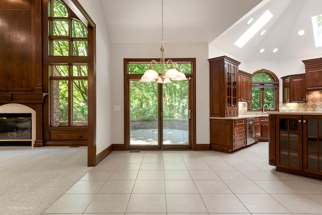 doorway to outside featuring a skylight, sink, a chandelier, light colored carpet, and a tiled fireplace